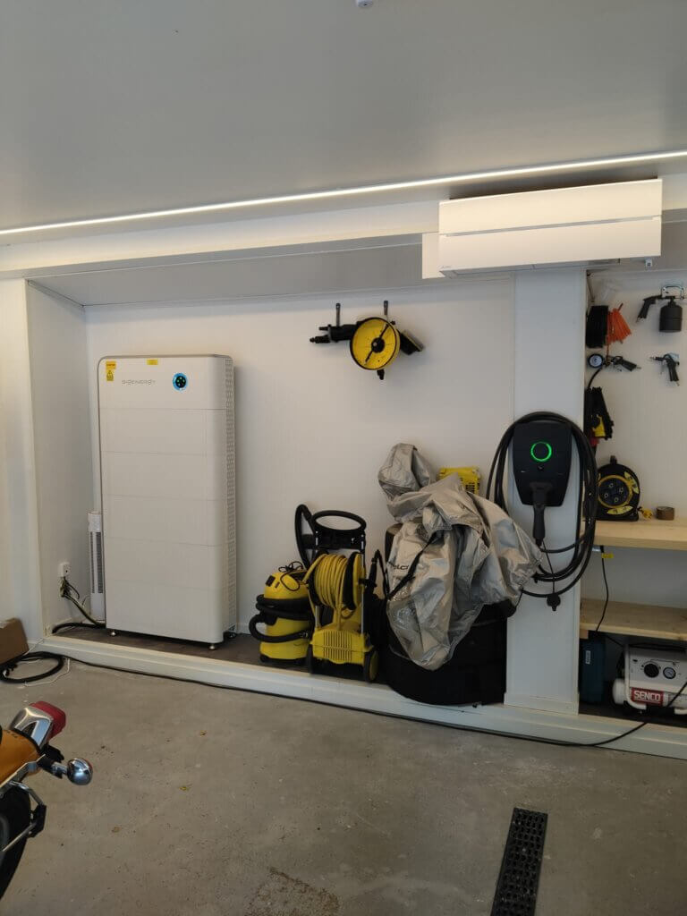 Ett stort vitt Sigenergy-batteri och en Zaptec-laddbox installerade snyggt och prydligt inuti ett garage.