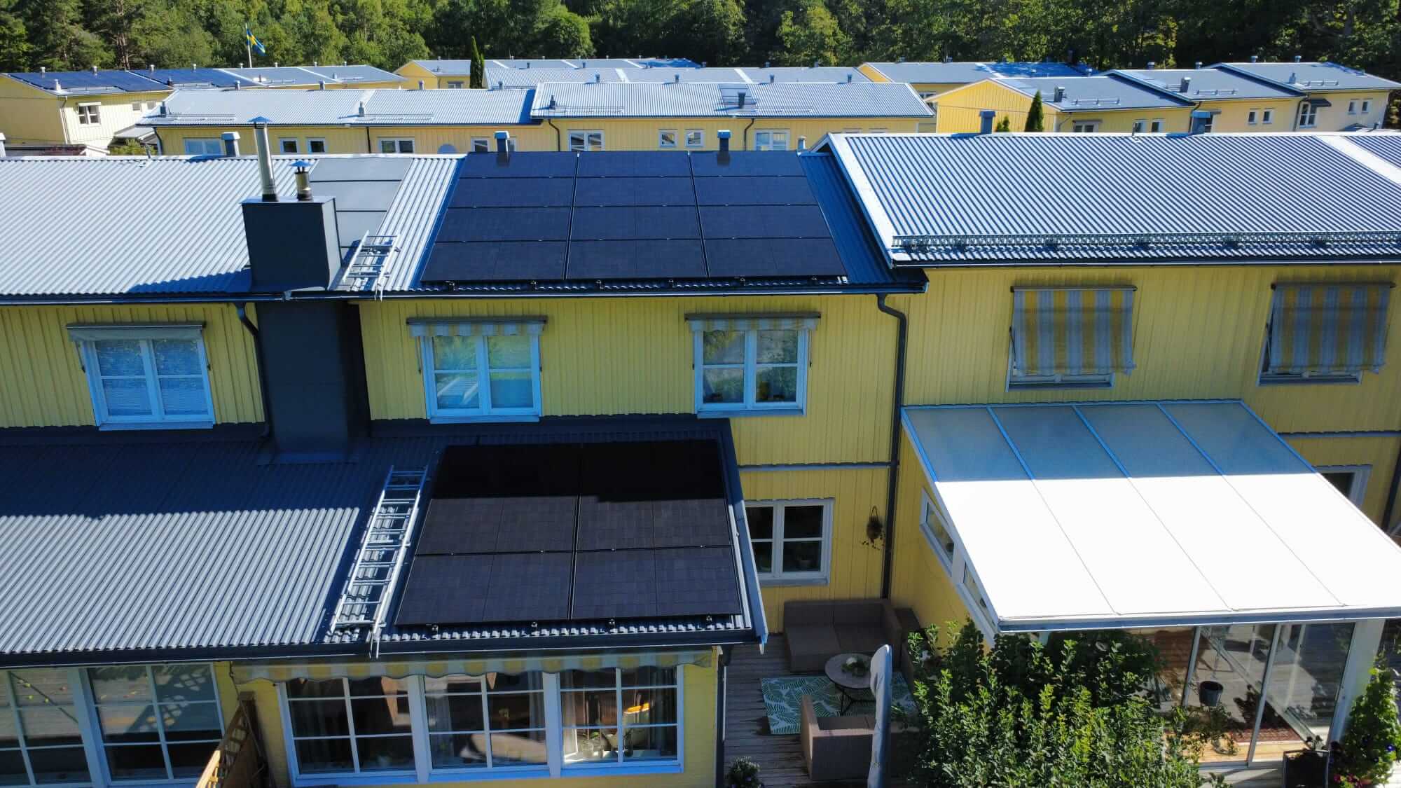 Flygbild över radhus i Gustavsberg med svarta Astronergy solpaneler monterade på två olika taknivåer.