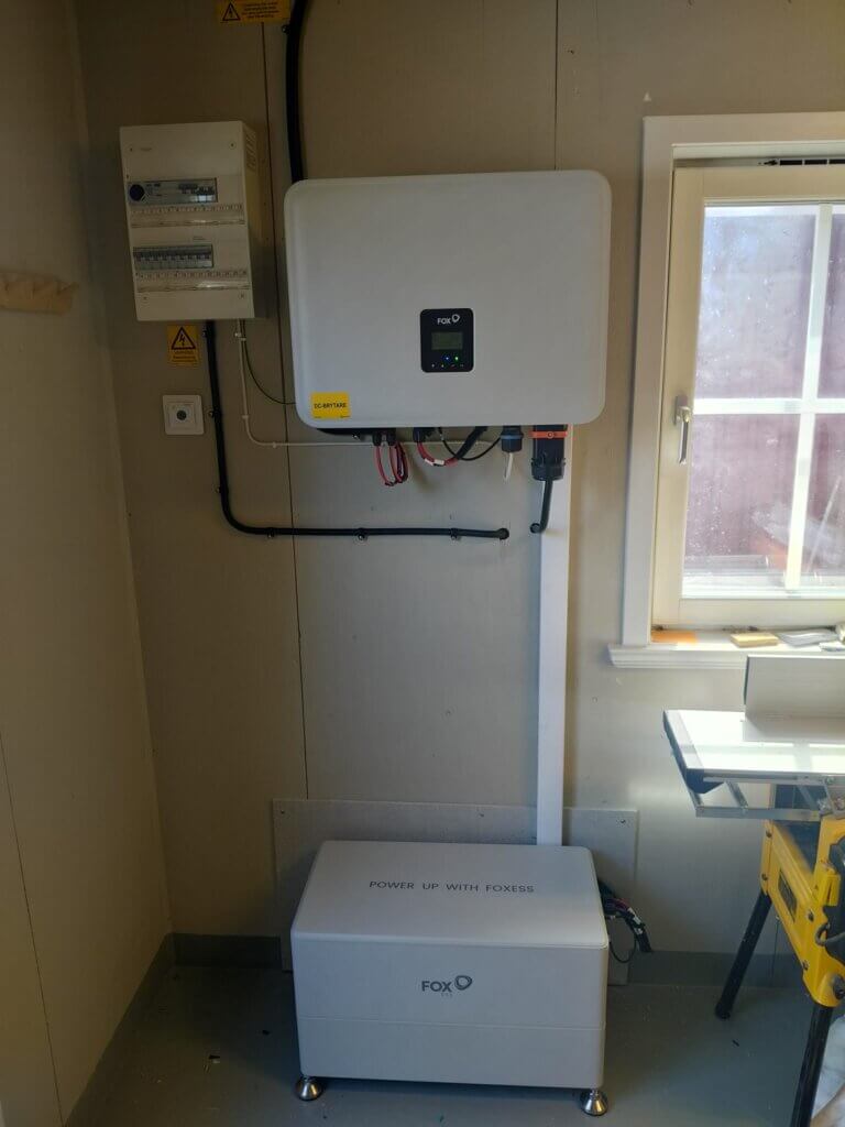 Vit FoxESS växelriktare på väggen och FoxESS EQ6000 batteri på 12 kWh snyggt installerat på golvet i ett garage.