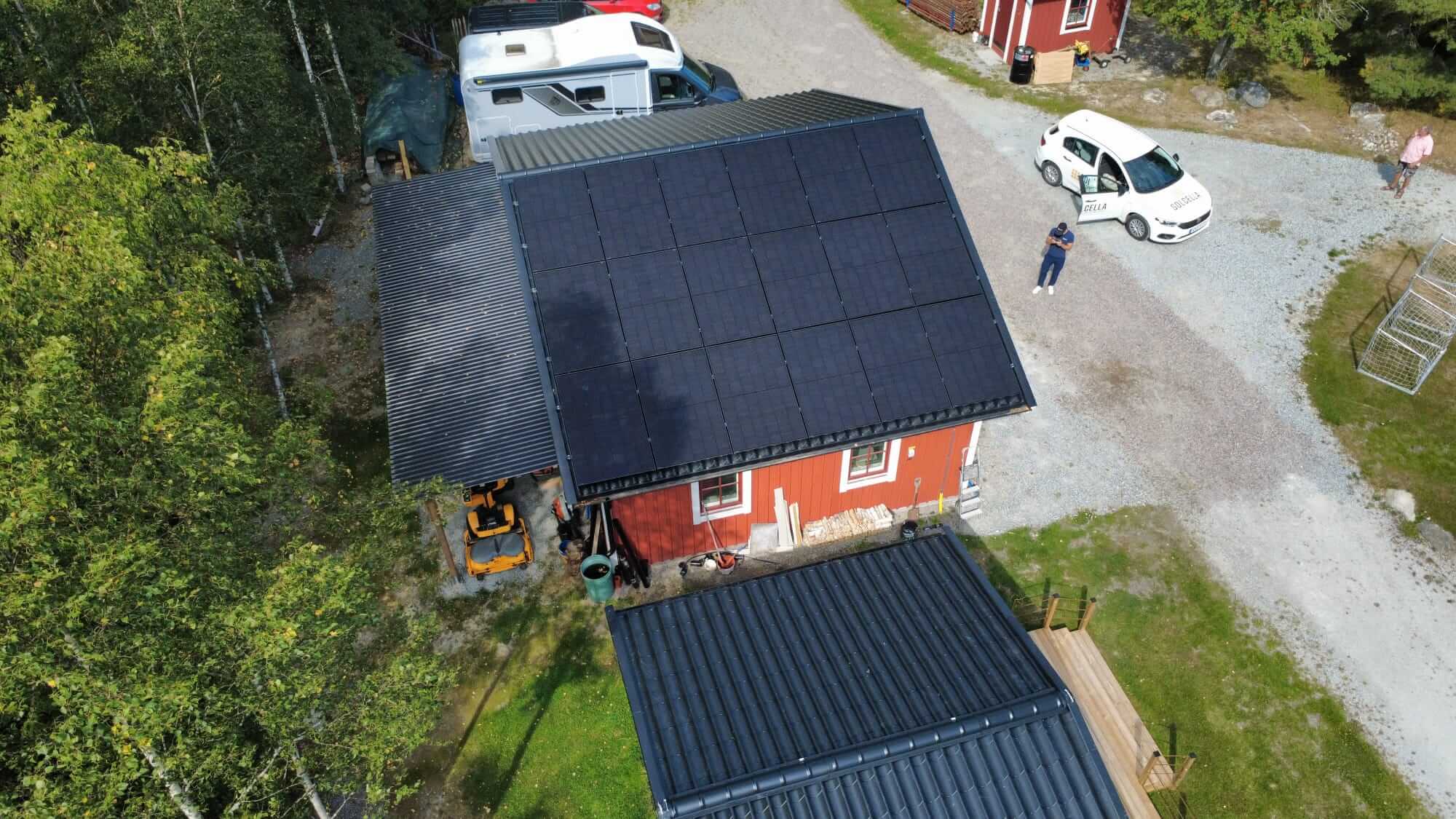Drönarbild över ett rött garage i Enhörna där hela det södervända taket täcks av svarta solceller installerade av Solcella.
