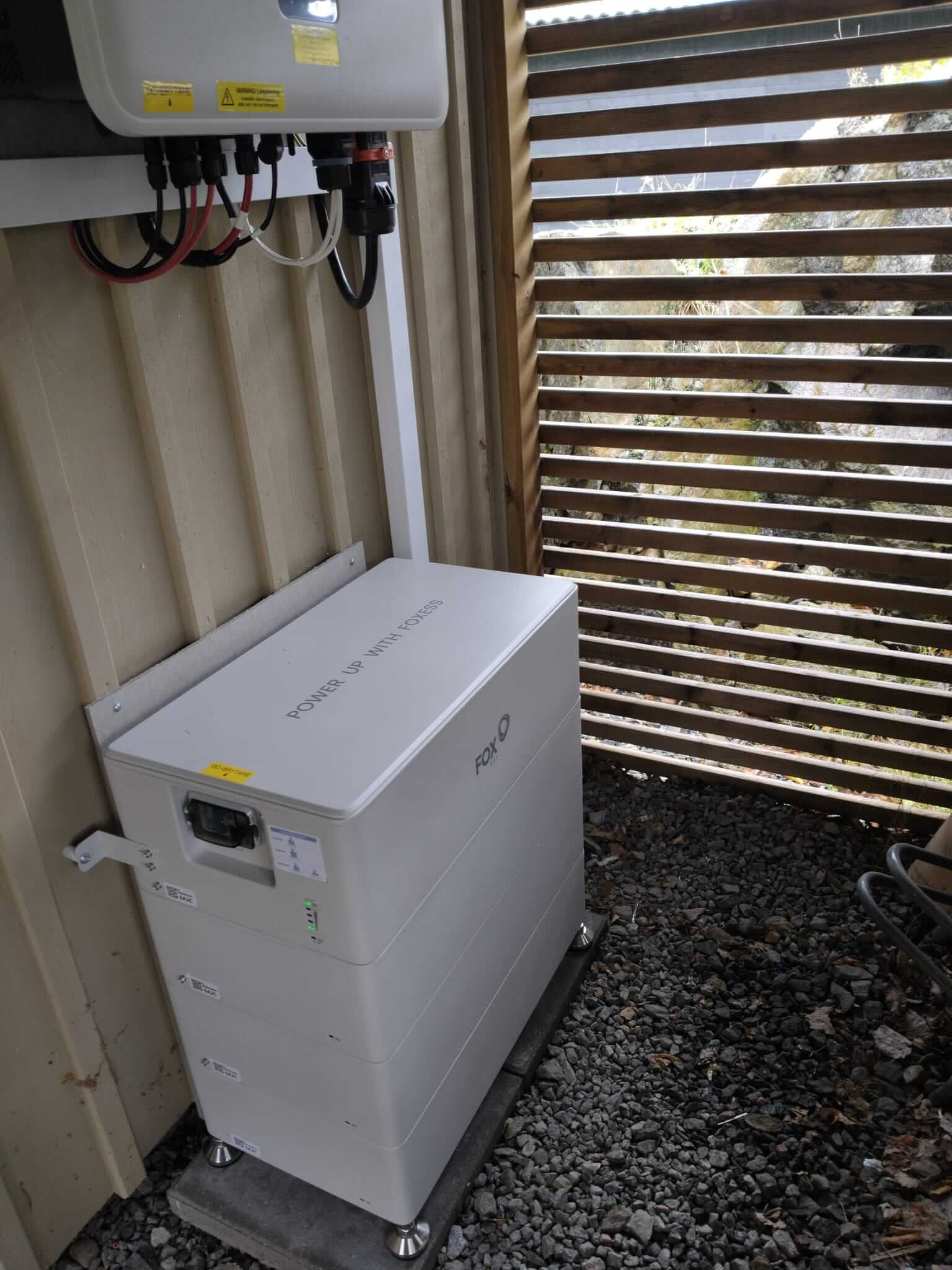 FoxESS 24 kWh batteri och 15 kW växelriktare installerat vid fasad under träaltan i Tullinge