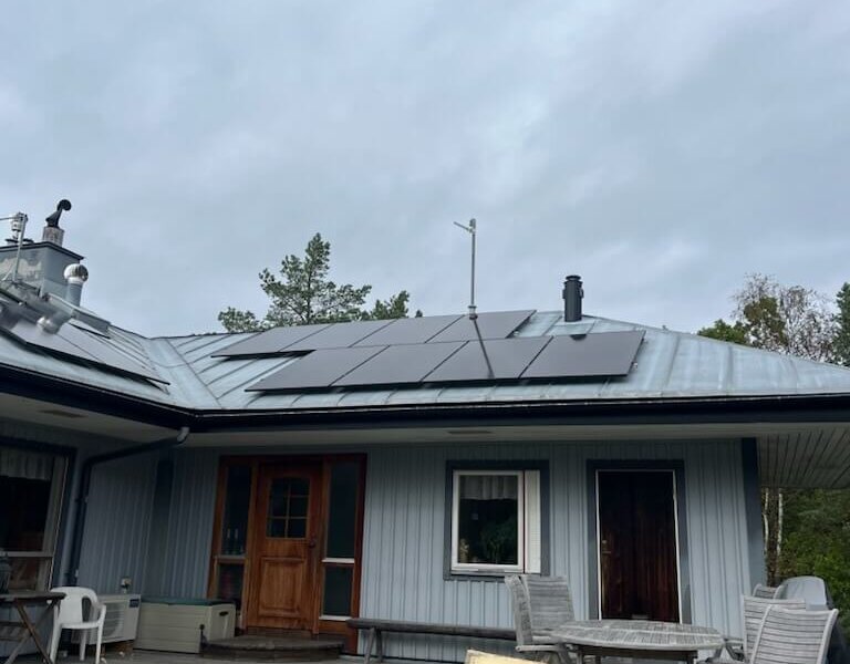 Svarta solpaneler monterade på falsat plåttak på skärgårdsfastighet på Västra Delsholmen utanför Möja.