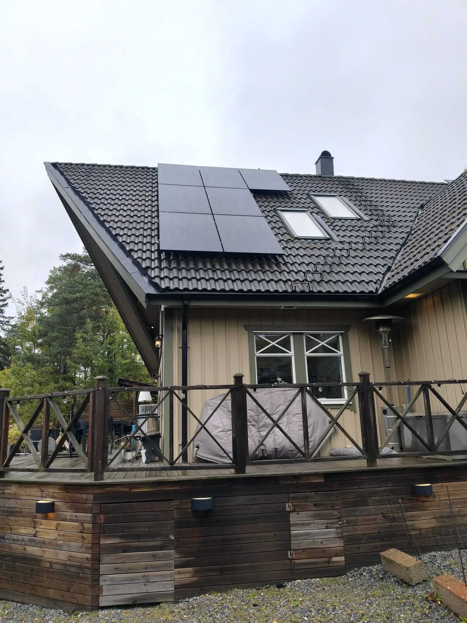 Svarta solcellspaneler installerade invid takkupa och takfönster ovanför altan i Tullinge
